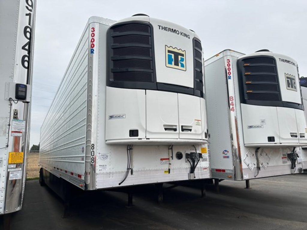 Utility 3000R trailer with Thermo King unit on front, white reefer trailer, two units visible in a lot, front facade shows cooling units and HT logo.