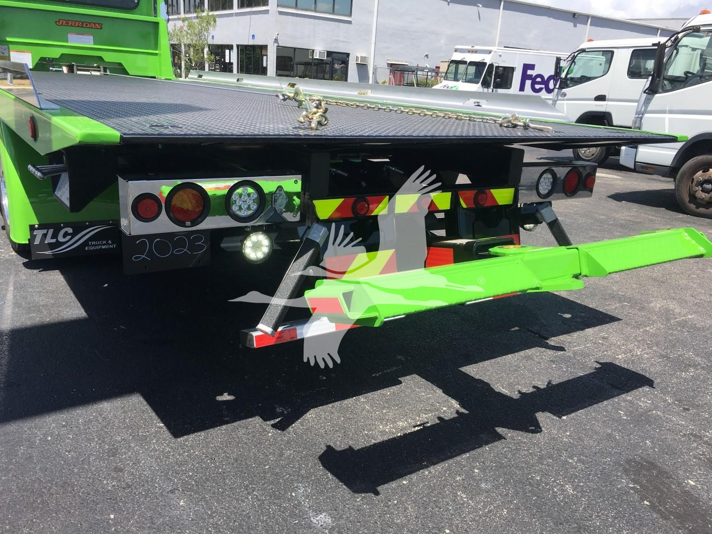 Truck rear view showing green steel rollback equipment with reflective tape and taillights on a Peterbilt 337 chassis.