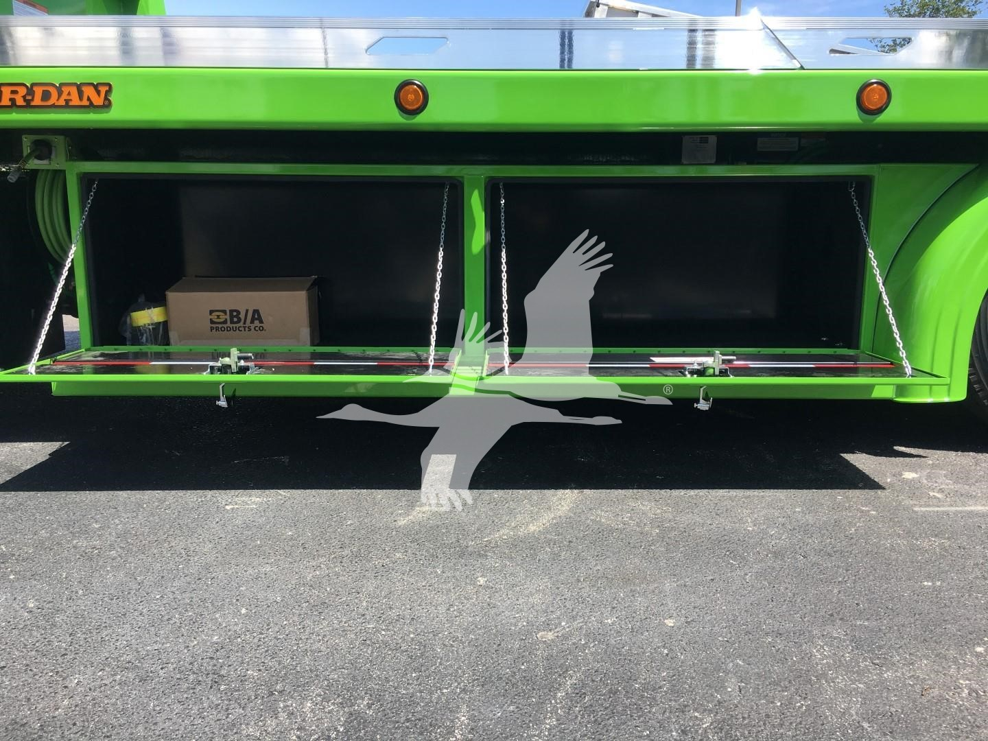 Truck bed storage compartments open showing two compartments with a cardboard box in left one, bright green Peterbilt rollback body, stock number J52310 in listing.