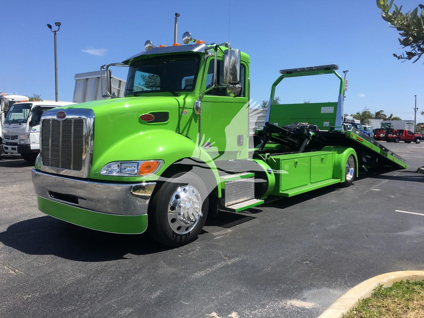 Green 2022 Peterbilt 337 rollback tow truck side view showing long wheelbase and flatbed with ramp, chrome bumper, large grille, and dual rear wheels.