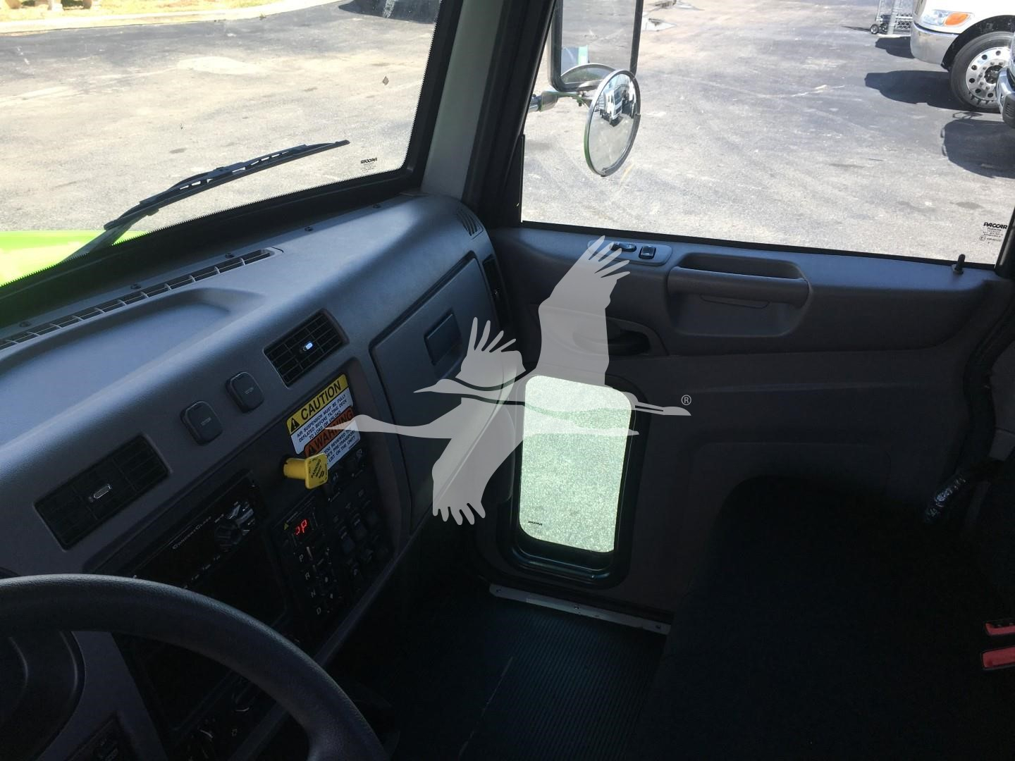 Peterbilt 337 cab interior showing dashboard with control panel, steering wheel, and door; driver-side window and side mirror visible.