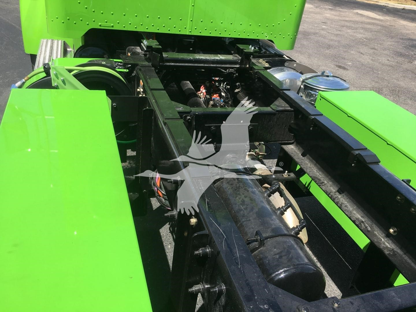 Green Peterbilt 337 chassis frame view showing drivetrain components and frame rails.