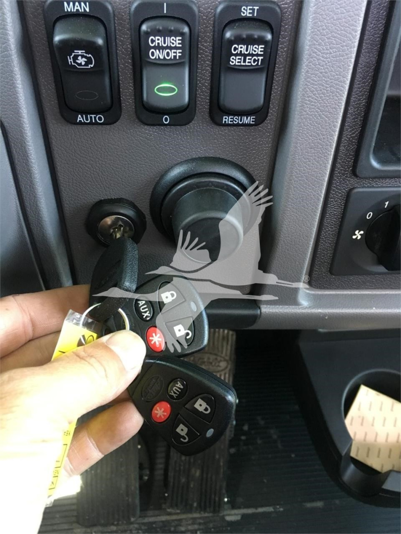 Truck interior: ignition area with key fob and buttons labeled MAN, CRUISE ON/OFF, CRUISE SELECT, set/resume. Keys and fob on hand near steering column.