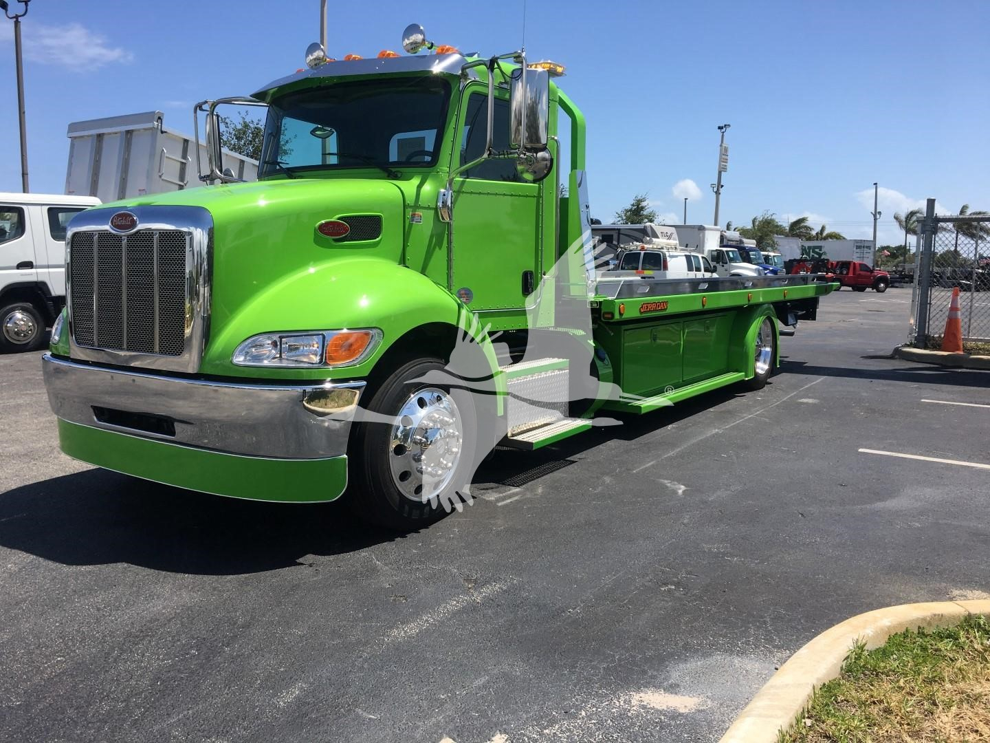 Green Peterbilt 337 rollback tow truck side view showing bright chrome grille and flatbed.