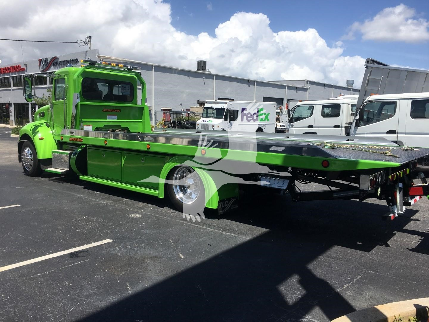 Green Peterbilt 337 rollback tow truck with flatbed, side view showing cab, chrome wheels, and rear loading bed.