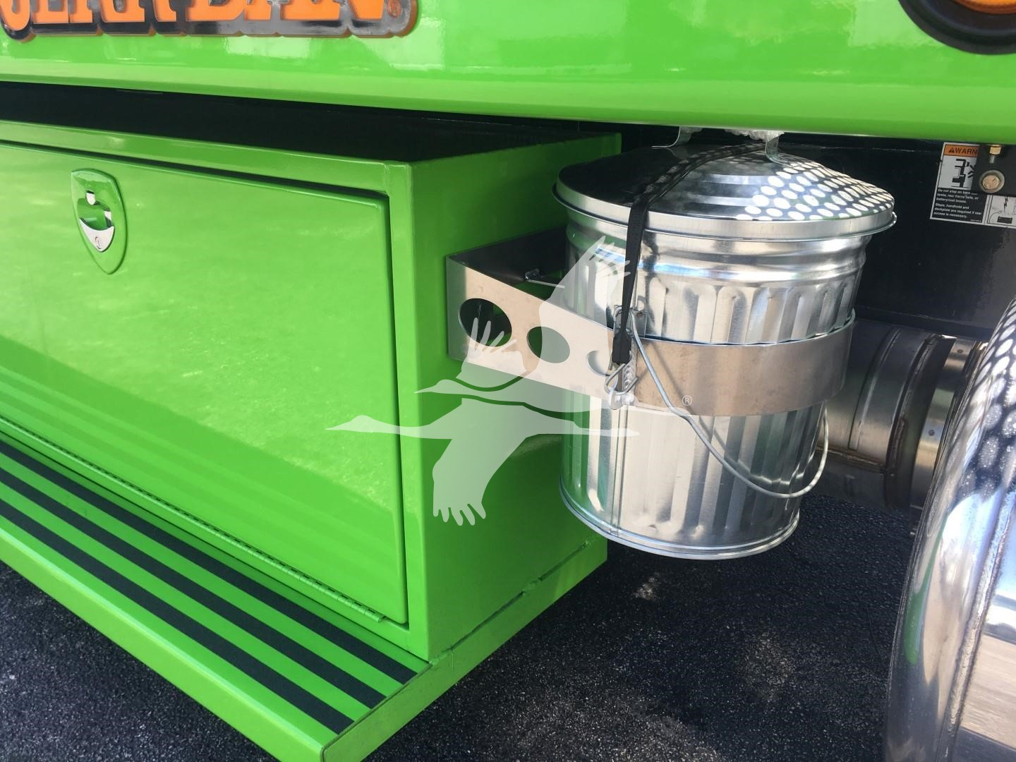 Green Peterbilt 337 rollback truck side with cylindrical chrome exhaust/muffler and silver diamond-plate top showing various compartments.