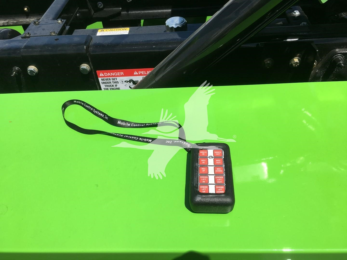Peterbilt 337 rollback with bright green hood; keyless keypad on hood; lanyard with badge and warning labels visible.