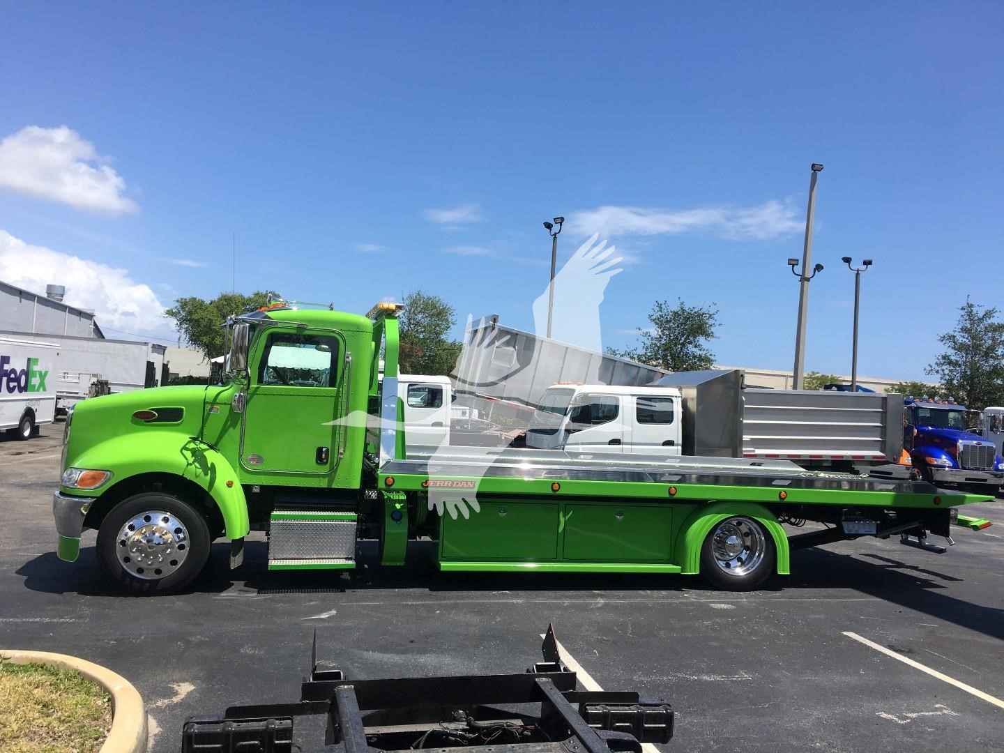 Green Peterbilt 337 rollback tow truck side view. Visible text includes stock number J52310 on dealership tag.