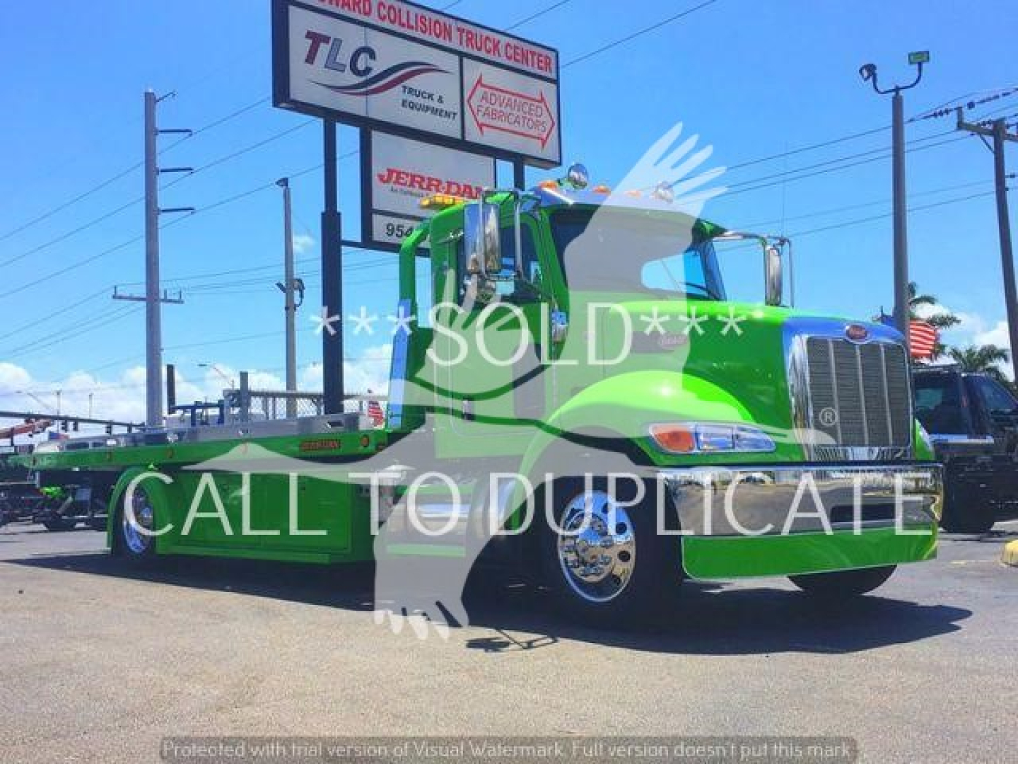 Peterbilt 337 rollback truck in green livery, front three-quarter view showing cab, chrome grille, and flatbed, with stock number J52310 visible and a dealership sign in background.