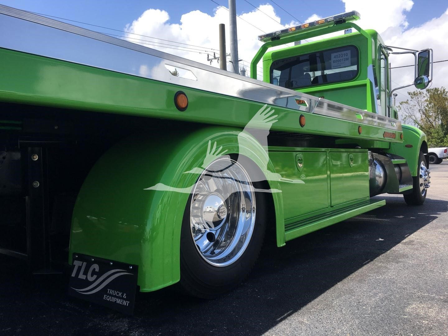 Peterbilt 337 rollback truck in bright green, side view showing chrome wheel, fender, and machinery with TLC logo on mudflap.