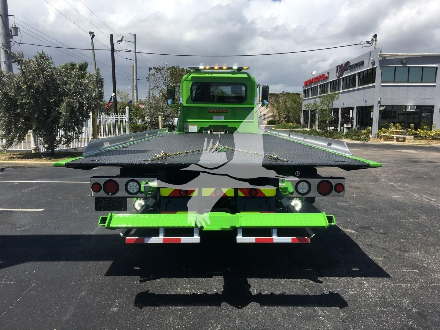 Green Peterbilt rollback tow truck rear view showing flatbed with taillights, mirrors, and bumper; stock number J52310 visible in listing context.