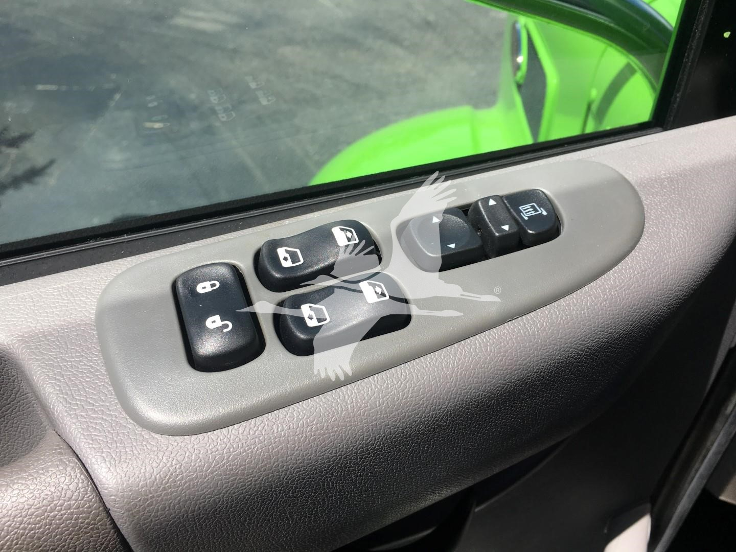 Vehicle interior door panel with window and mirror control switches on a Peterbilt truck, including multiple black buttons located in an oval gray housing.