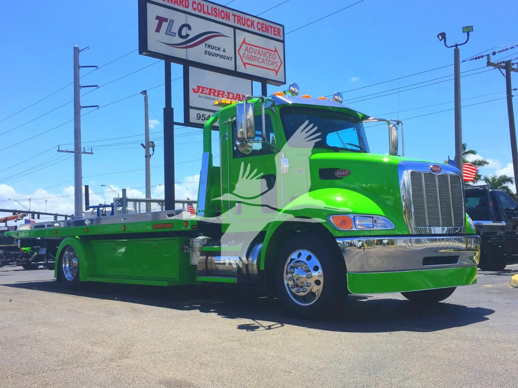 Green Peterbilt 337 rollback tow truck with chrome bumper, signboard in background displaying TLC and JERRETT? text, stock number J52310.