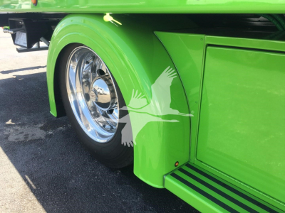 Truck fender and door area of a green 2022 Peterbilt 337 rollback truck showing chrome wheel and side step.