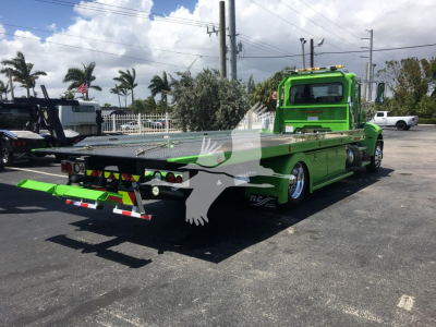 Green 2022 Peterbilt 337 rollback tow truck with flatbed, rear view showing lights and reflective stickers.