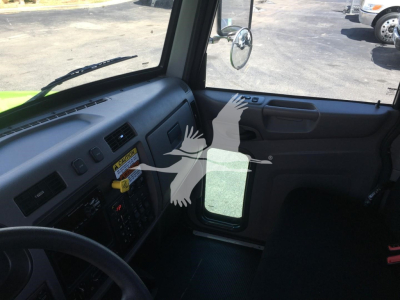 Peterbilt 337 cab interior showing dashboard with control panel, steering wheel, and door; driver-side window and side mirror visible.