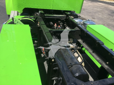 Green Peterbilt 337 chassis frame view showing drivetrain components and frame rails.