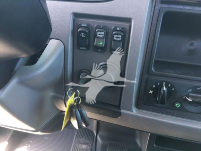 Peterbilt 337 dash panel with cruise control buttons and ignition keys visible in a rollback truck interior.