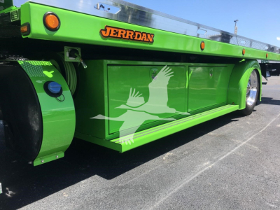 Green Peterbilt rollback truck side with cargo box and JERR-DAN logo, graphic of white flying bird on lower side panel.