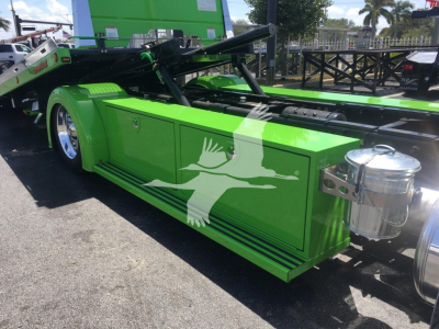 Green Peterbilt 337 rollback truck side storage compartments and chrome fuel tanks visible