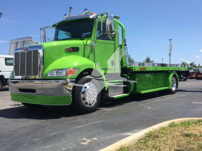 Peterbilt 337 rollback tow truck in bright green with chrome grille and flatbed, side view showing large wheel arch and fuel tanks.
