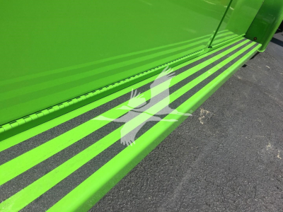 Side view of a bright green Peterbilt truck with black striping along the lower door area, showing glossy metal surface and part of a step.