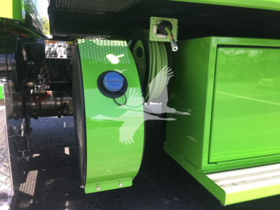 Green Peterbilt rollback truck component with reel and storage compartment visible, showing a circular blue cap and hydraulic line fittings.