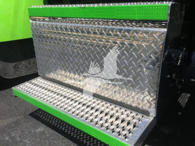 Truck step/side panel with diamond plate pattern and green accents; metallic toolbox with textured surface attached to a Peterbilt 337 rollback truck.