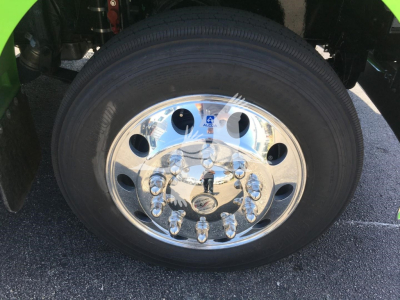 Wheel close-up of a Peterbilt 337 truck showing a polished chrome hubcap and lug nuts; tire mounted on steel/rim with reflections