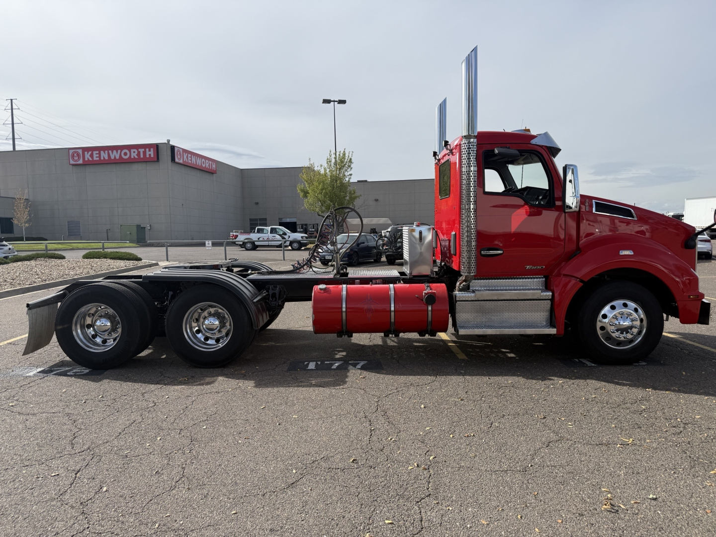Kenworth T880 conventional daycab truck in red, side view, showcasing chassis and fuel tanks.