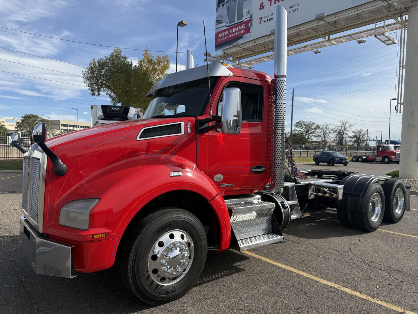 Kenworth T880 Conventional Daycab tractor in red, front-left view, showing side steps, chrome fuel tanks, and dual rear axles.