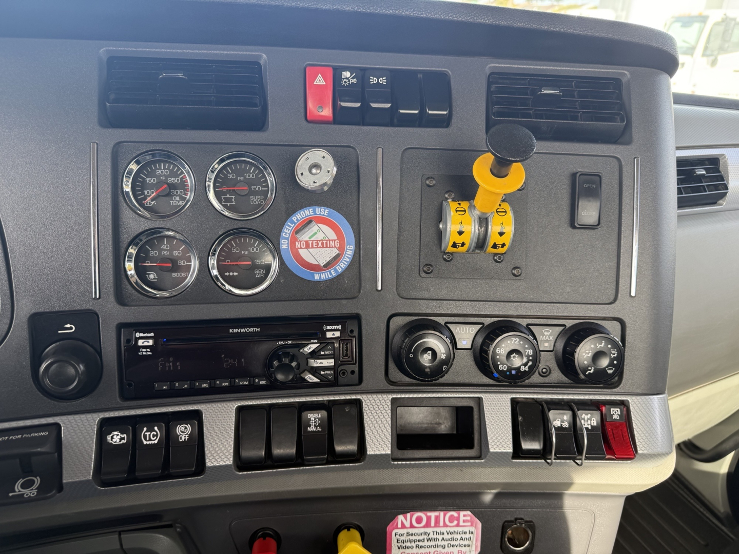 Dashboard of a 2020 Kenworth T880 showing four round gauges, ignition switches, and a yellow control lever. Visible text includes VIN/stock info not on panel, Hazard light button, and various switches.