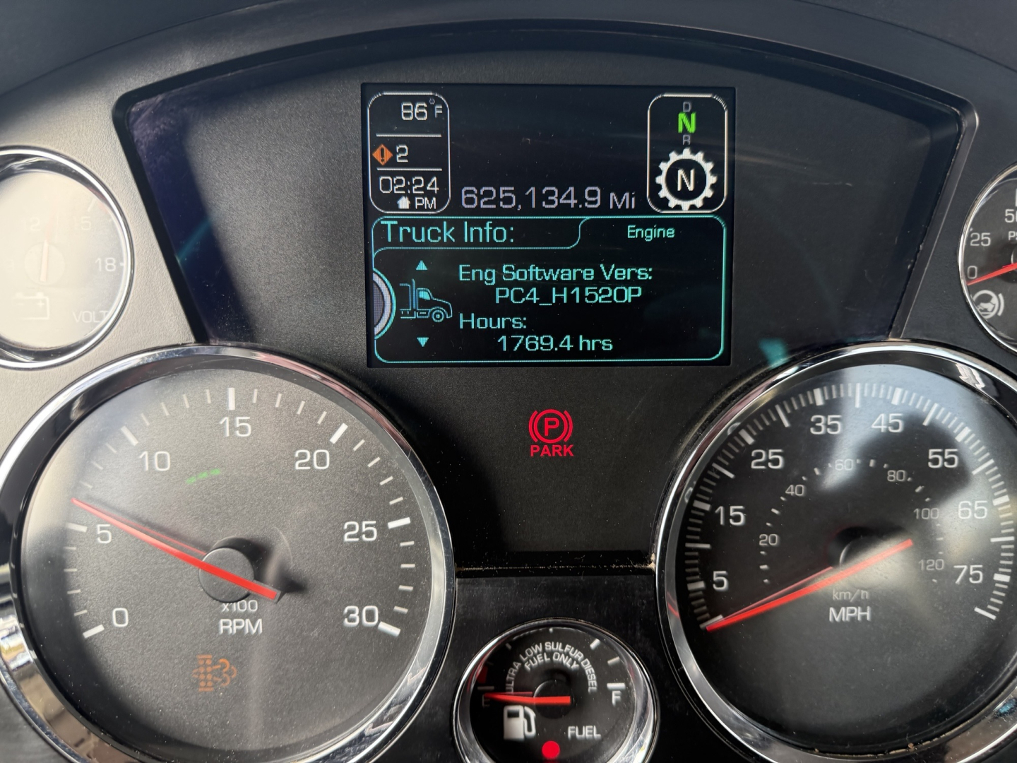 Dashboard display on Kenworth T880 showing engine software version and hours, with large analog gauges for RPM and speed. Center screen reads Eng Software Vers: PC4_H1520P, Hours: 1769.4 hrs, Truck Info: Engines, and gear indicator N.