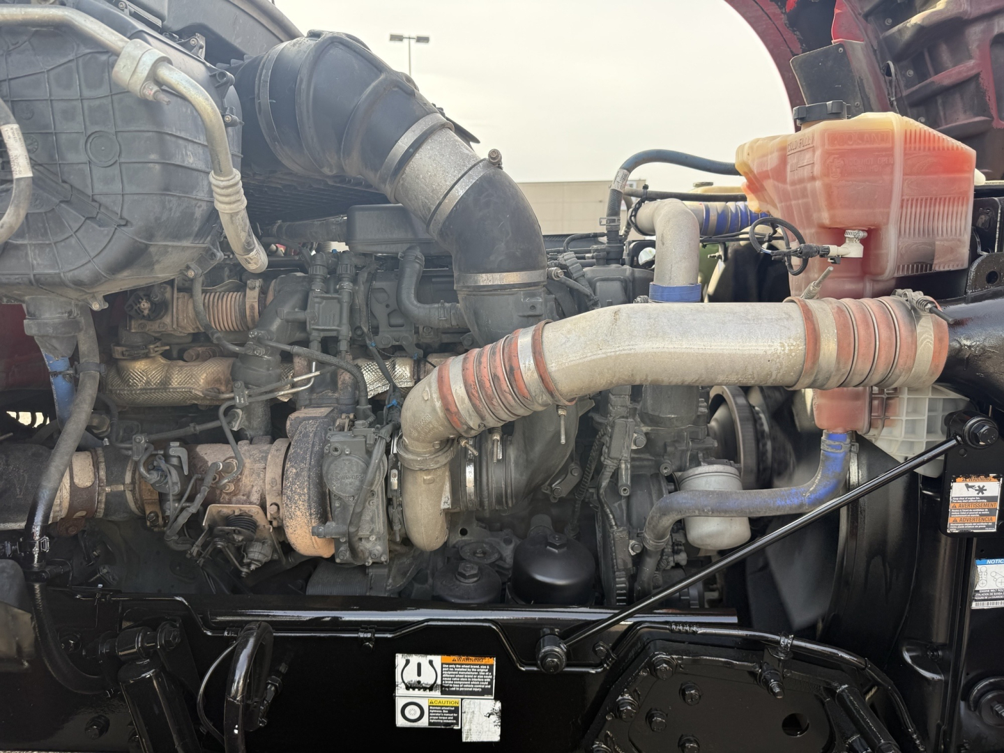 Kenworth T880 engine bay with hoses, coolant reservoir, and air intake visible.
