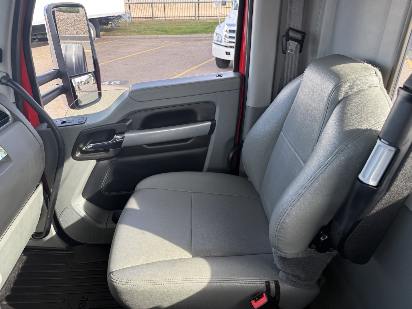 Kenworth T880 cab interior with gray fabric seat and truck door panel, front window view showing steering area.