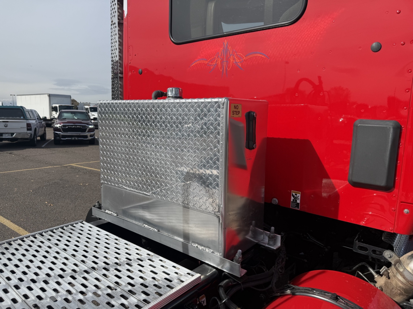 Kenworth T880 truck cab rear view showing aluminum toolbox and diamond plate steps.