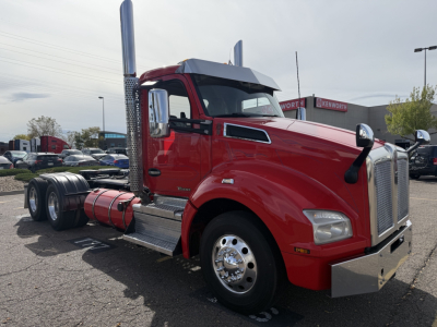 Kenworth T880 conventional daycab truck in red, side view showing chrome exhaust stacks, fuel tanks, and front grille; no visible text aside from model styling.