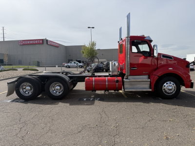 Kenworth T880 conventional daycab truck in red, side view, showcasing chassis and fuel tanks.