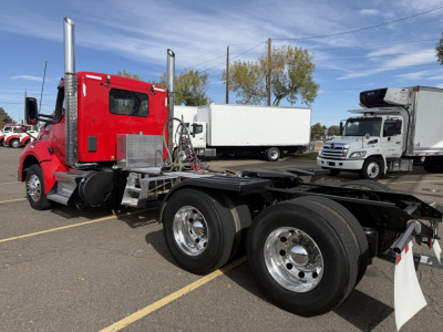 Kenworth T880 chassis in red cab with dual rear axles and chrome wheels, visible fuel tanks and hoses; tag shows 2020 model year in a truck yard.