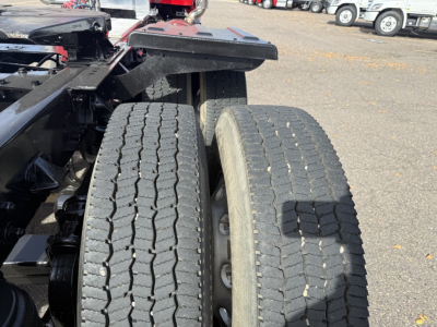 Kenworth T880 truck chassis and dual rear axles with dual tires in a yard, on-highway truck frame and suspension components visible between wheels.