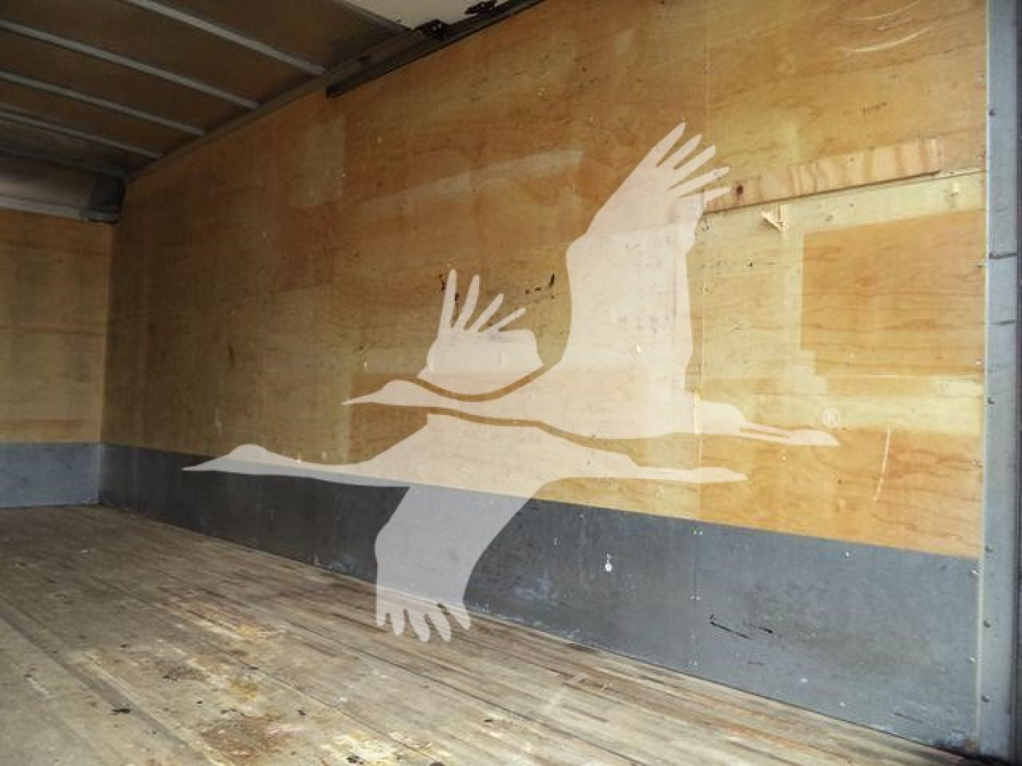 Isuzu NPR HD box truck cargo area interior with wooden walls and faded graphic of hands on the side.
