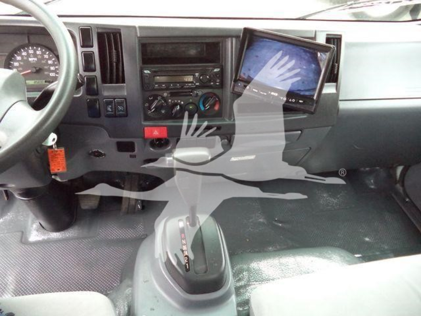 Isuzu NPR-HD cab interior showing dashboard with center console, gear shifter, and mounted tablet display.