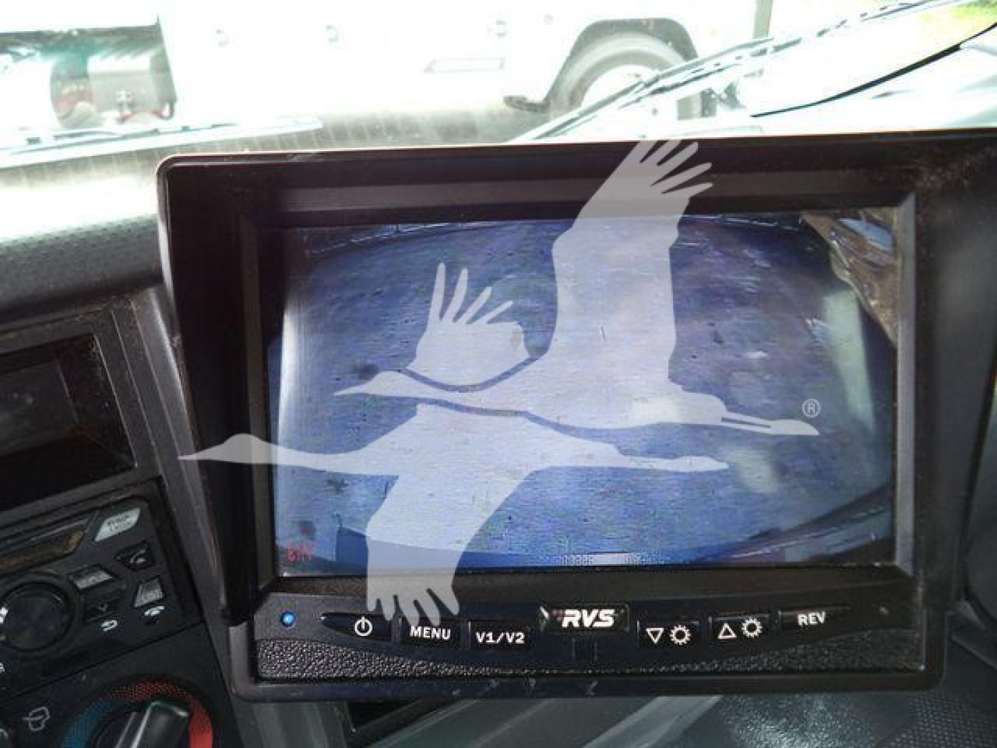 Isuzu NPR HD dashboard with aftermarket RVs/backup monitor displaying a blue-toned screen and control buttons visible below the screen.