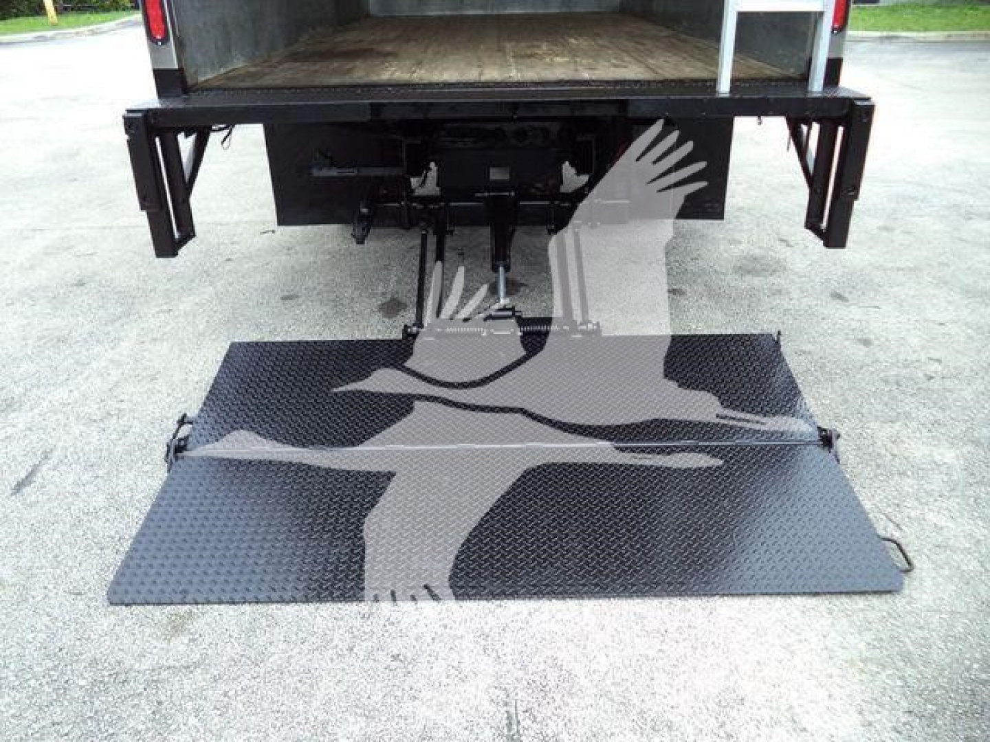 Isuzu NPR-HD truck rear view showing hydraulic lift/ramp extended with diamond plate surface.