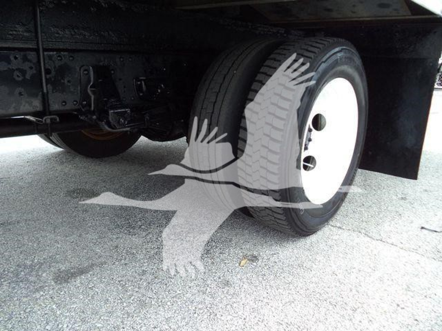 Isuzu NPR HD truck rear wheel/view showing white steel rim and dual rear axle, undercarriage and suspension components visible