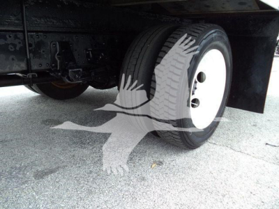 Isuzu NPR HD truck rear wheel/view showing white steel rim and dual rear axle, undercarriage and suspension components visible