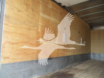 Truck cargo area with wooden walls and a white flying bird logo (Gull-wing logo) visible inside the truck.