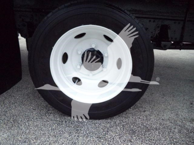 Wheel and tire of Isuzu NPR HD truck showing white steel rim and black tire, partial chassis in background.