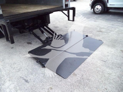 Isuzu NPR-HD truck with a fold-out aluminum loading ramp extended from the back of the box truck. Visible surface shows diamond plate texture.