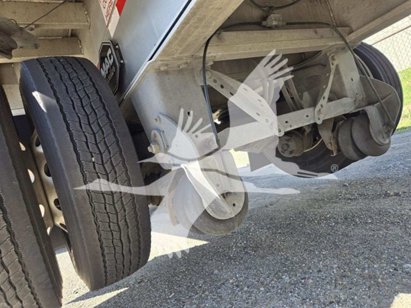 Flatbed trailer underside with dual rear wheels and suspension visible.